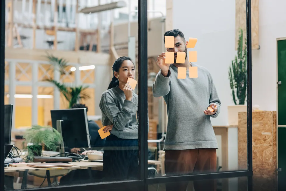 Two people planning with notes on a window