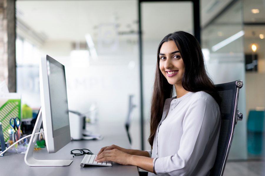 A smiling young woman working at a desktop computer