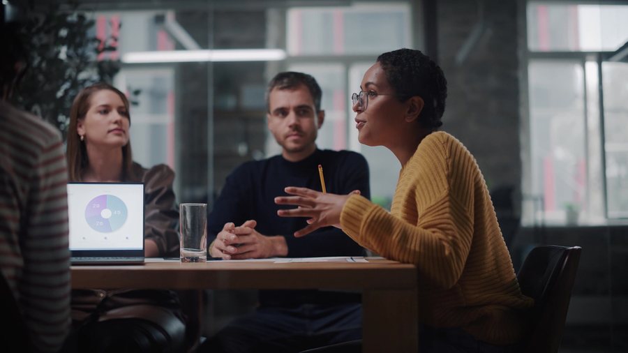 A recruiter in conversation with a hiring team around a table